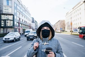 Woman with face mask standing outdoors on road in city, coronavirus concept.